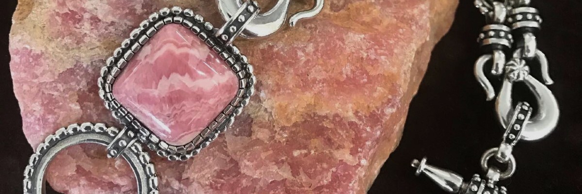 Rhodochrosite Sterling Silver Bracelet resting on Rhodochrosite rough stone in the Bowman Originals Lapidary Studio